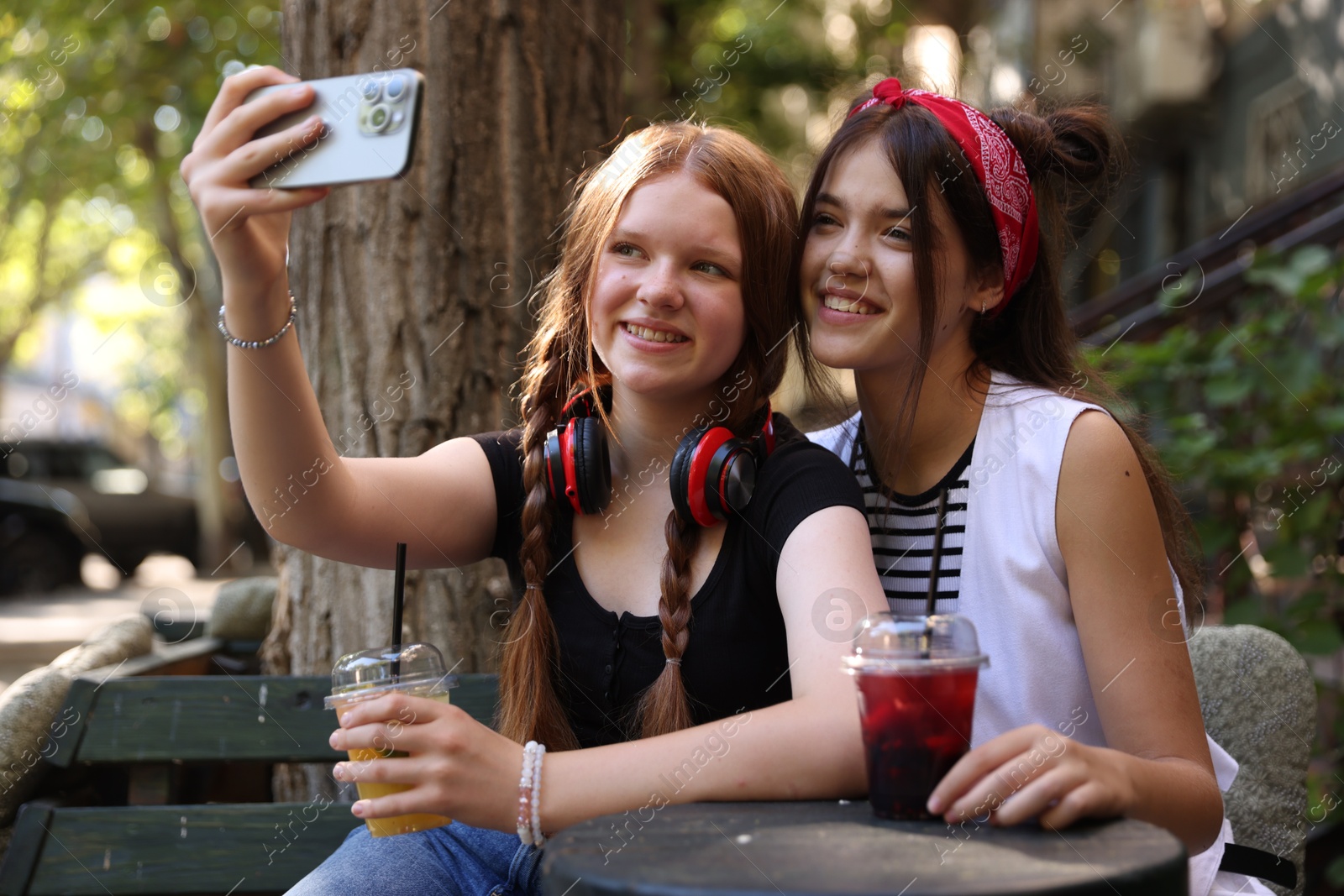 Photo of Happy teenage friends taking selfie in outdoor cafe