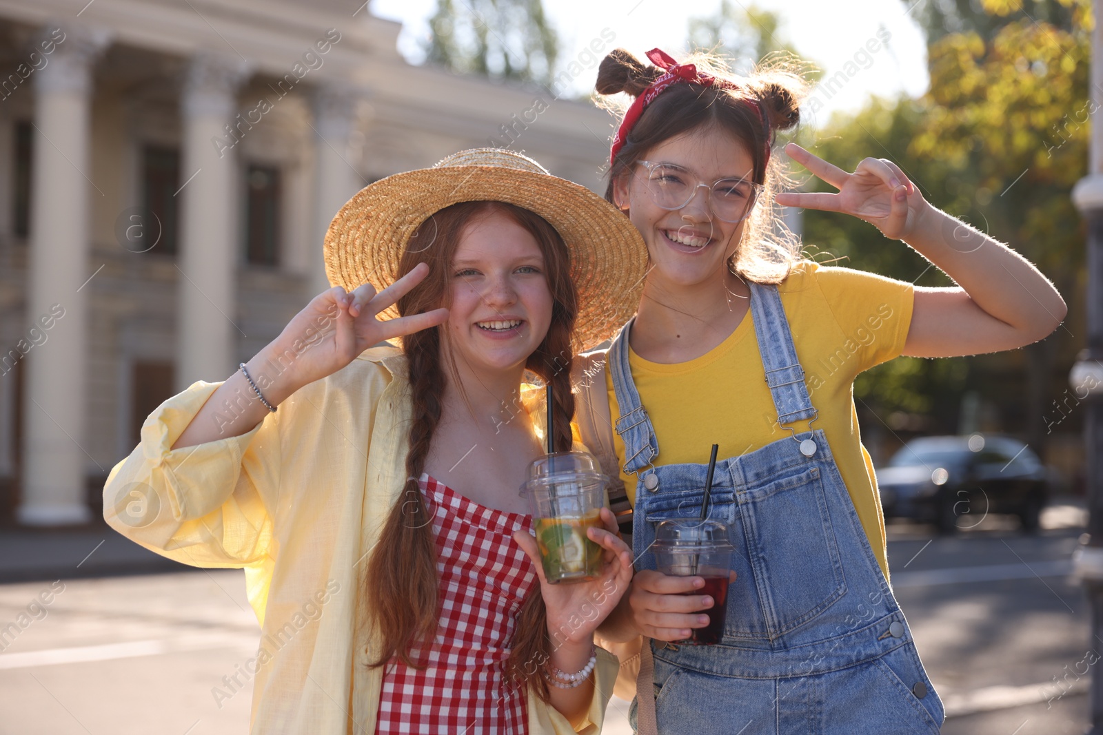 Photo of Happy teenage friends showing peace signs on city street