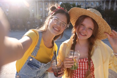 Happy teenage friends taking selfie on city street