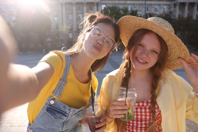 Photo of Happy teenage friends taking selfie on city street