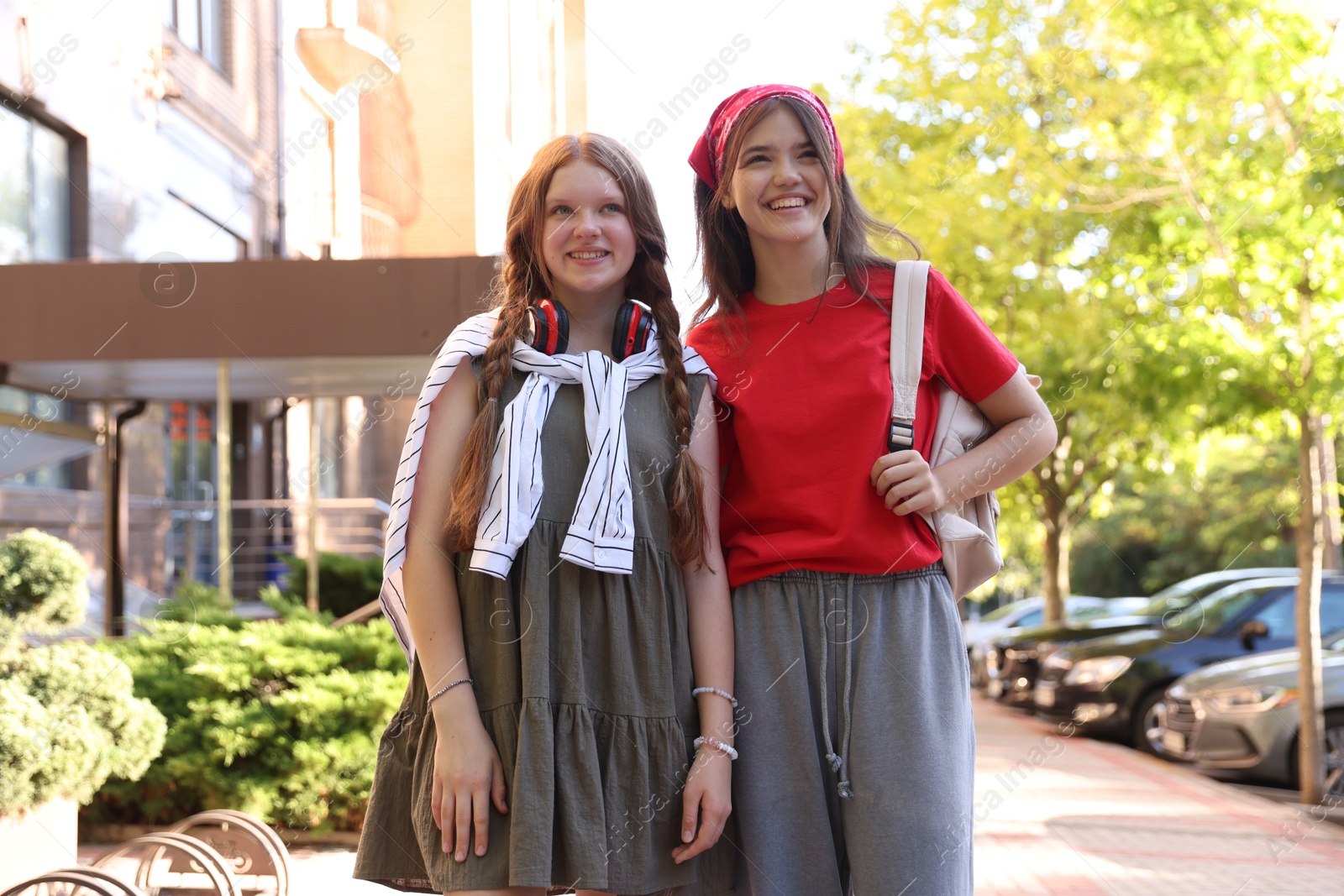 Photo of Happy teenage friends walking on city street