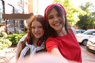 Happy teenage friends taking selfie on city street