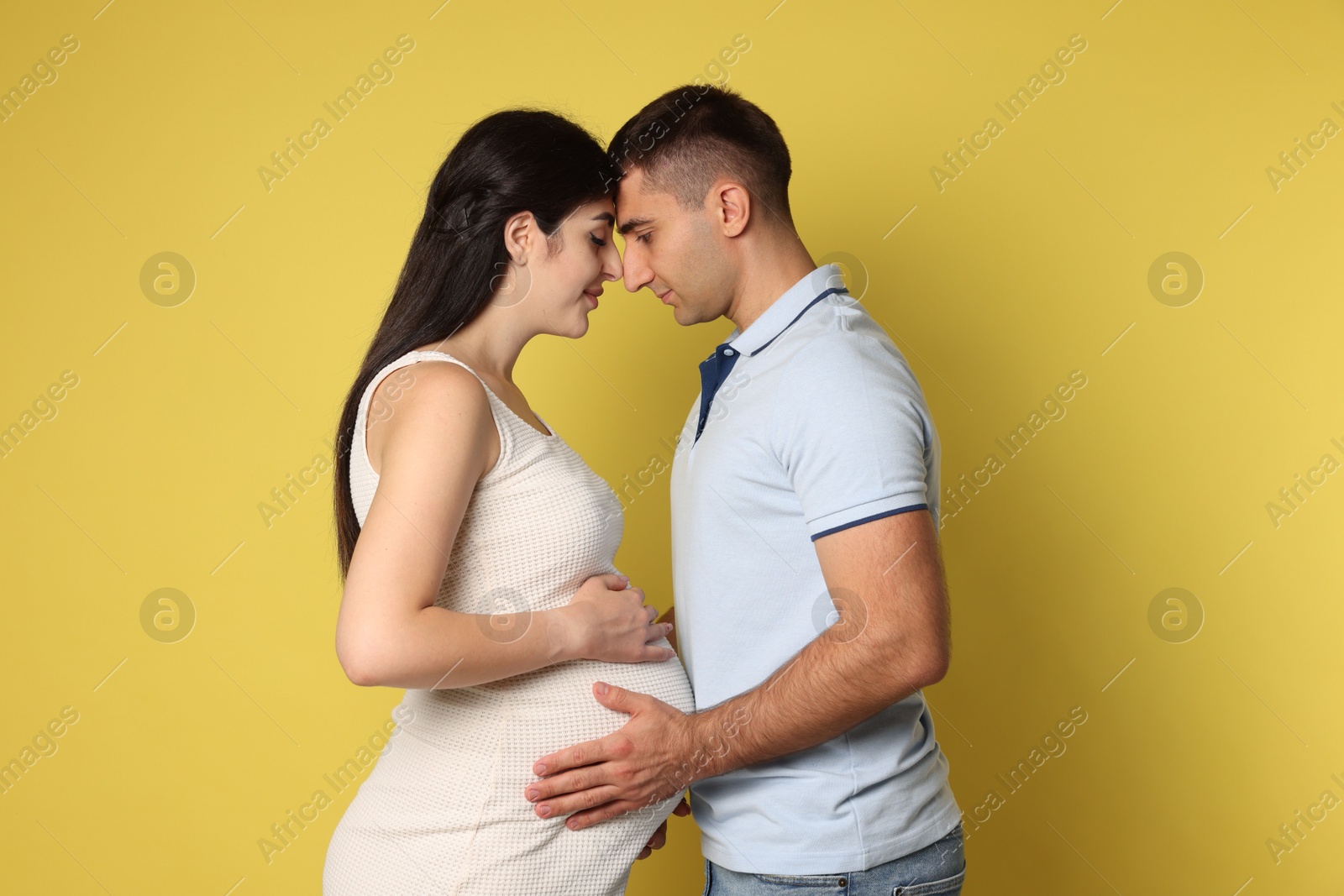 Photo of Beautiful pregnant woman with her husband on yellow background