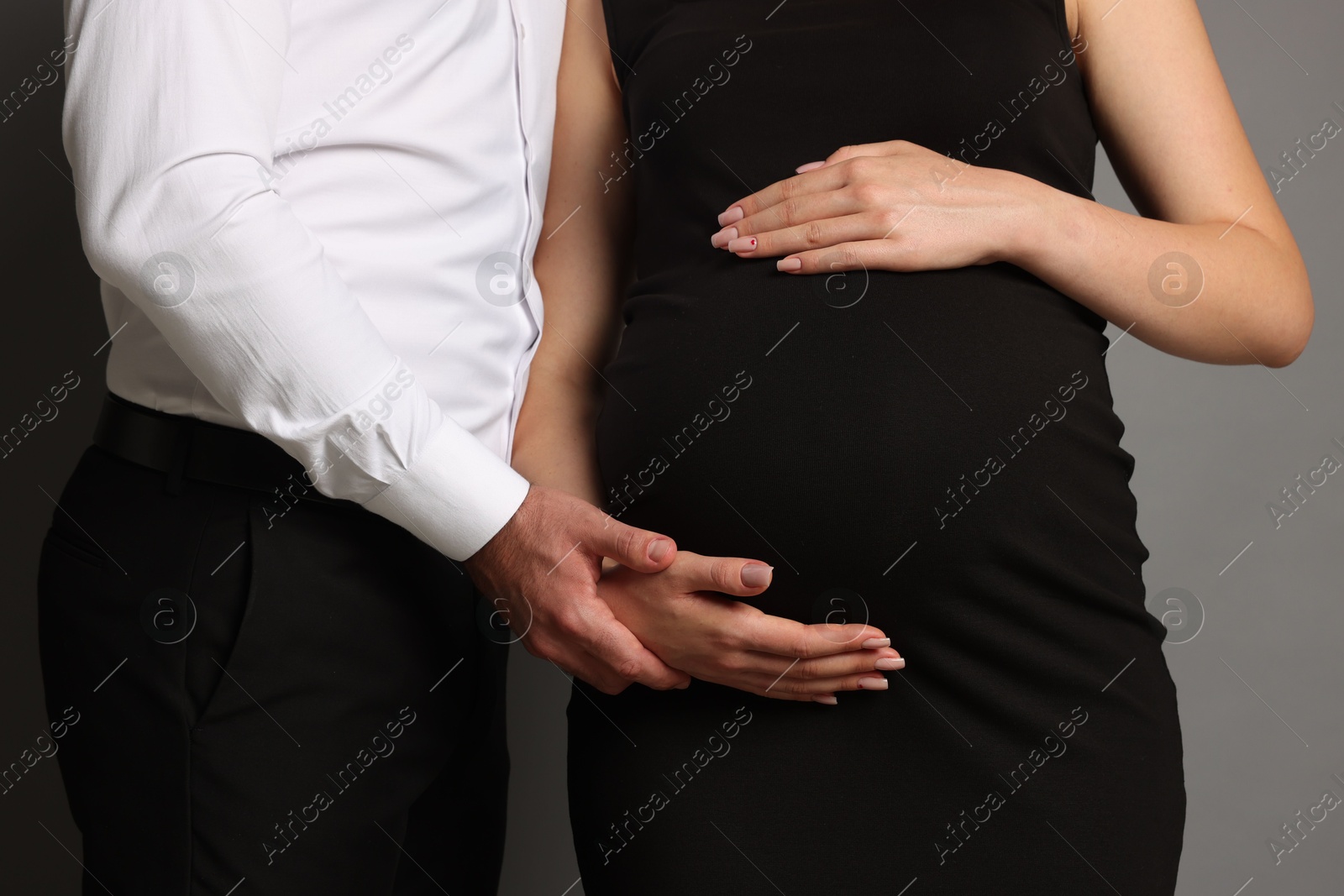 Photo of Pregnant woman with her husband on grey background, closeup