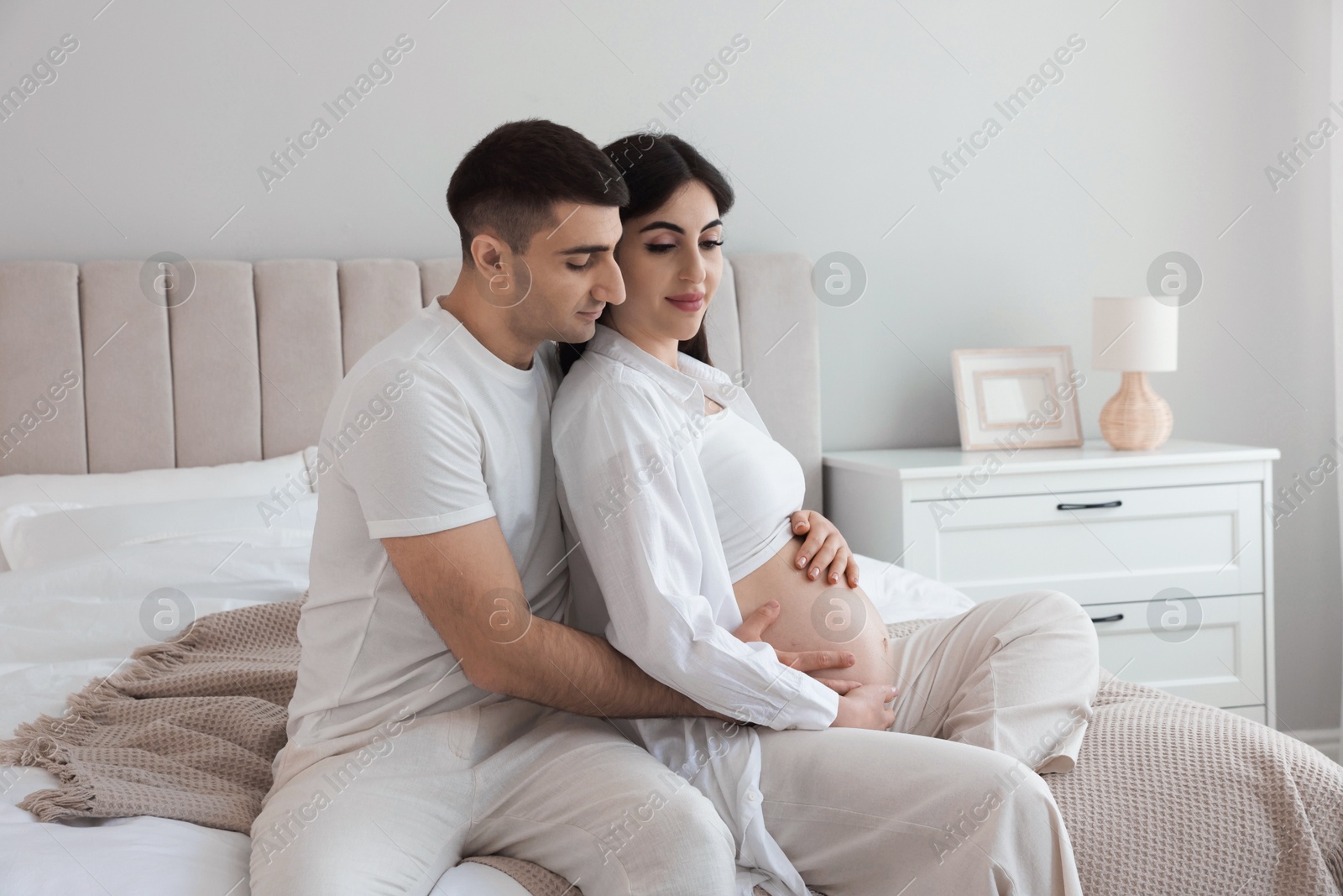 Photo of Beautiful pregnant woman spending time with her husband in bedroom