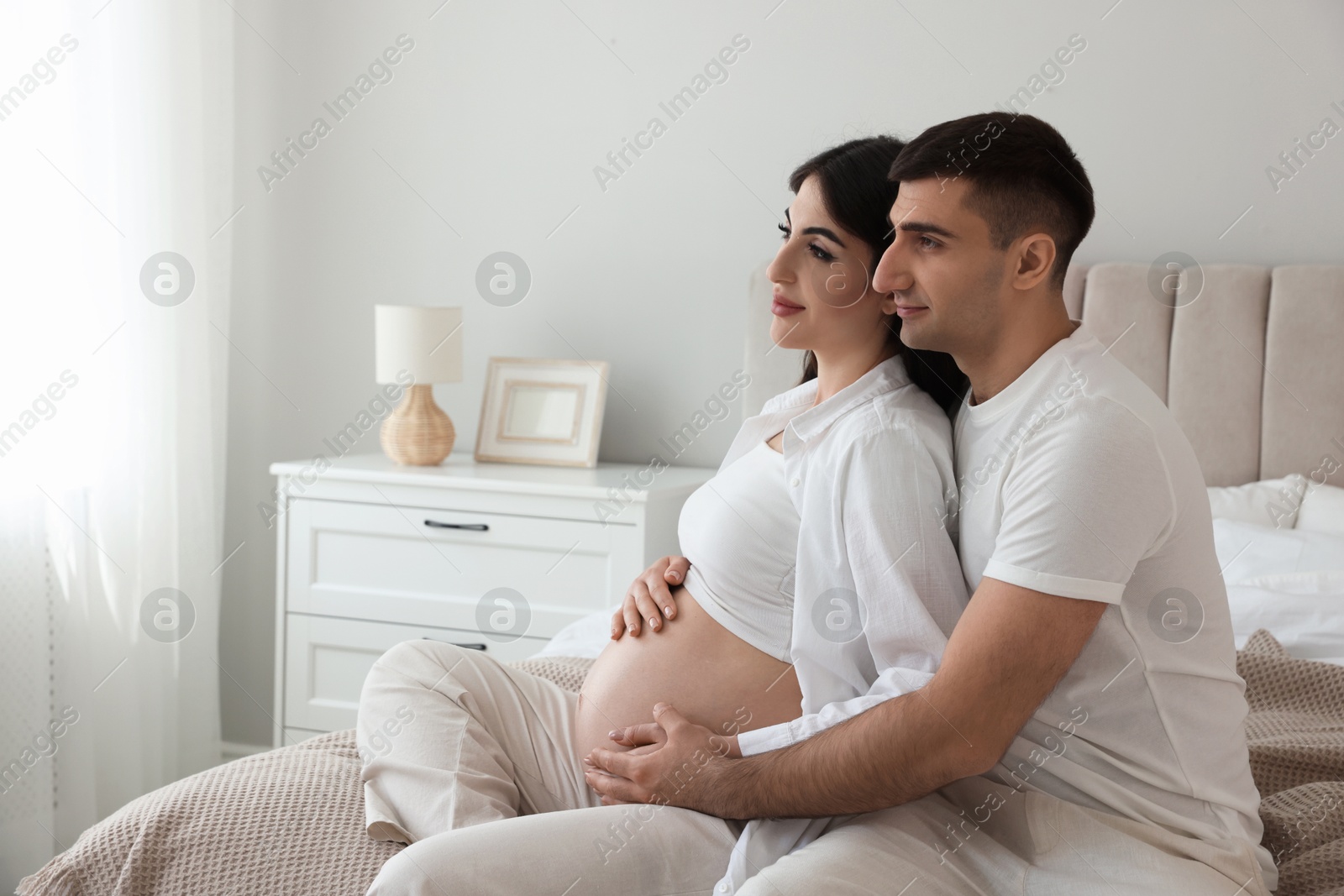 Photo of Beautiful pregnant woman spending time with her husband in bedroom