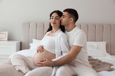 Photo of Beautiful pregnant woman spending time with her husband in bedroom