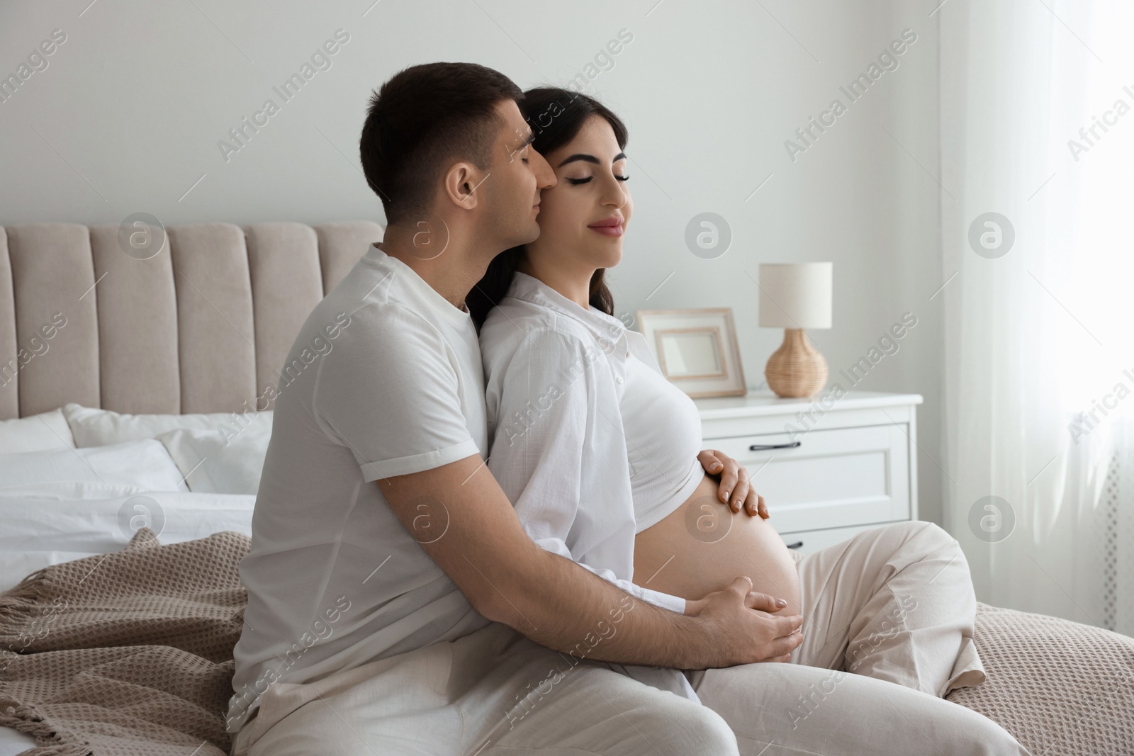 Photo of Beautiful pregnant woman spending time with her husband in bedroom