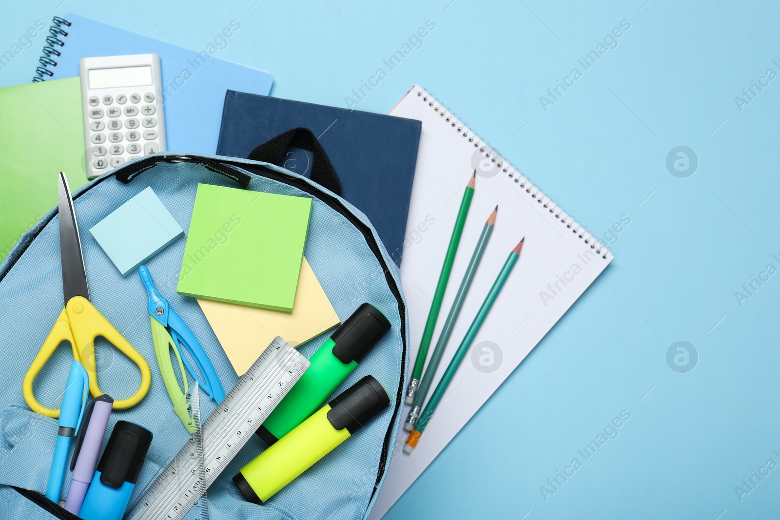 Photo of Backpack with different school stationery on light blue background, top view. Space for text