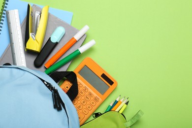 Photo of Light blue school backpack with stationery on green background, top view. Space for text