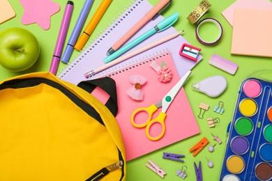 Photo of Backpack, different school stationery and apple on light green background, flat lay