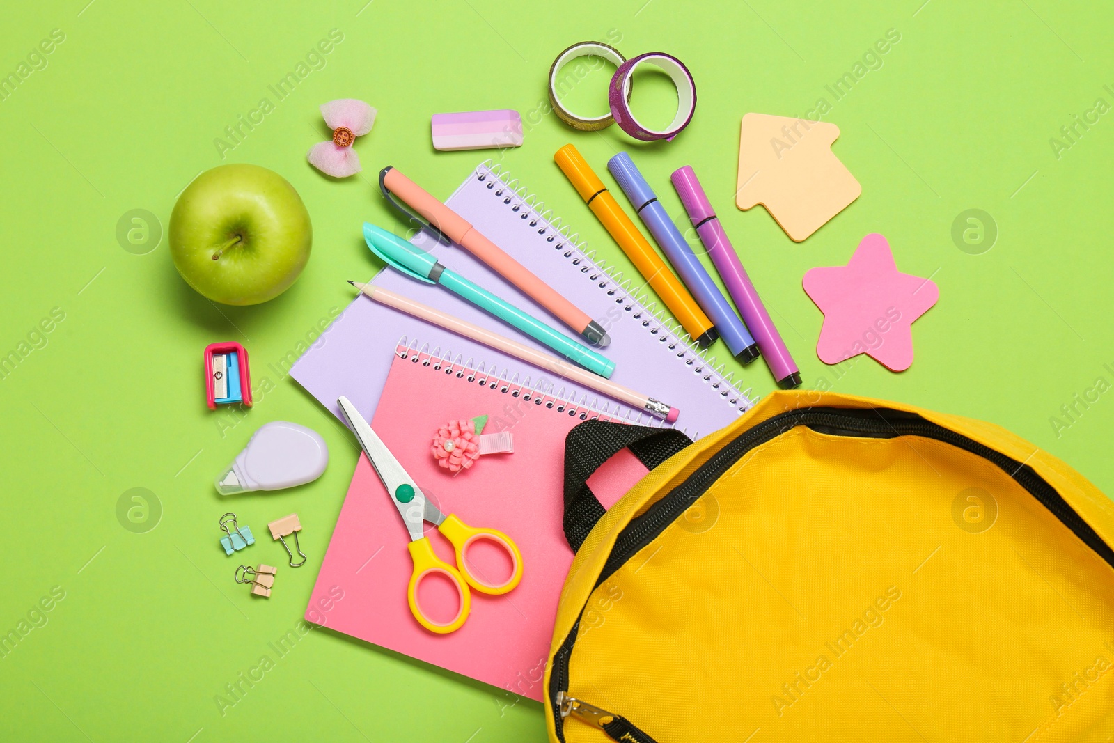 Photo of Backpack, different school stationery and apple on light green background, flat lay