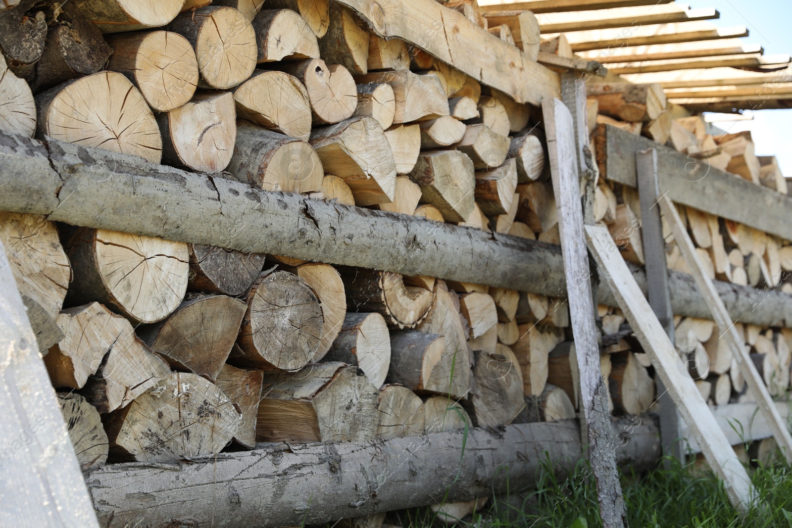 Photo of Stacked cut firewood on green grass outdoors