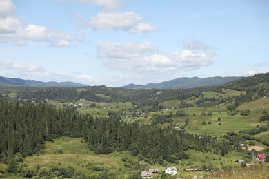 Photo of Picturesque view of houses and forest in mountains under blue sky