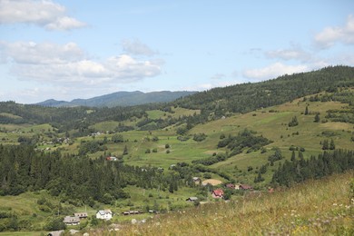 Photo of Picturesque view of houses and forest in mountains under blue sky