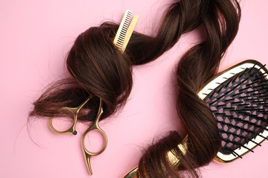 Brown hair strand, brush and professional scissors on pink background, top view