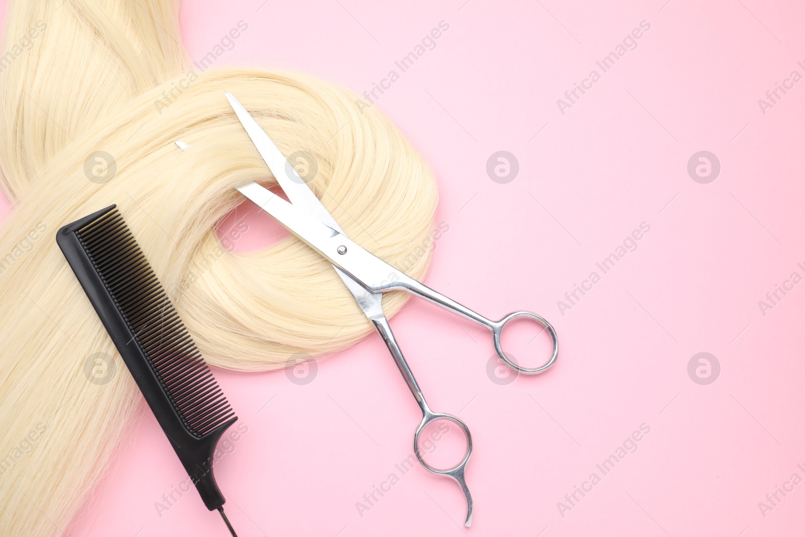 Photo of Blonde hair strand, comb and professional scissors on pink background, top view