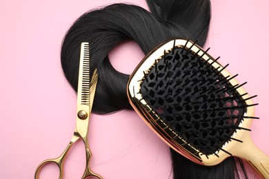 Black hair strand, brush and professional scissors on pink background, top view