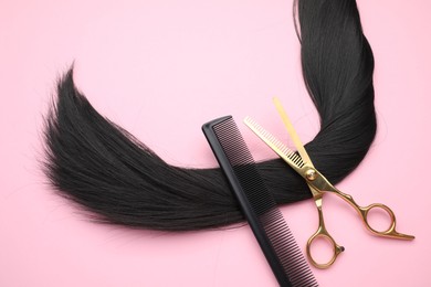 Photo of Black hair strand, comb and professional scissors on pink background, top view