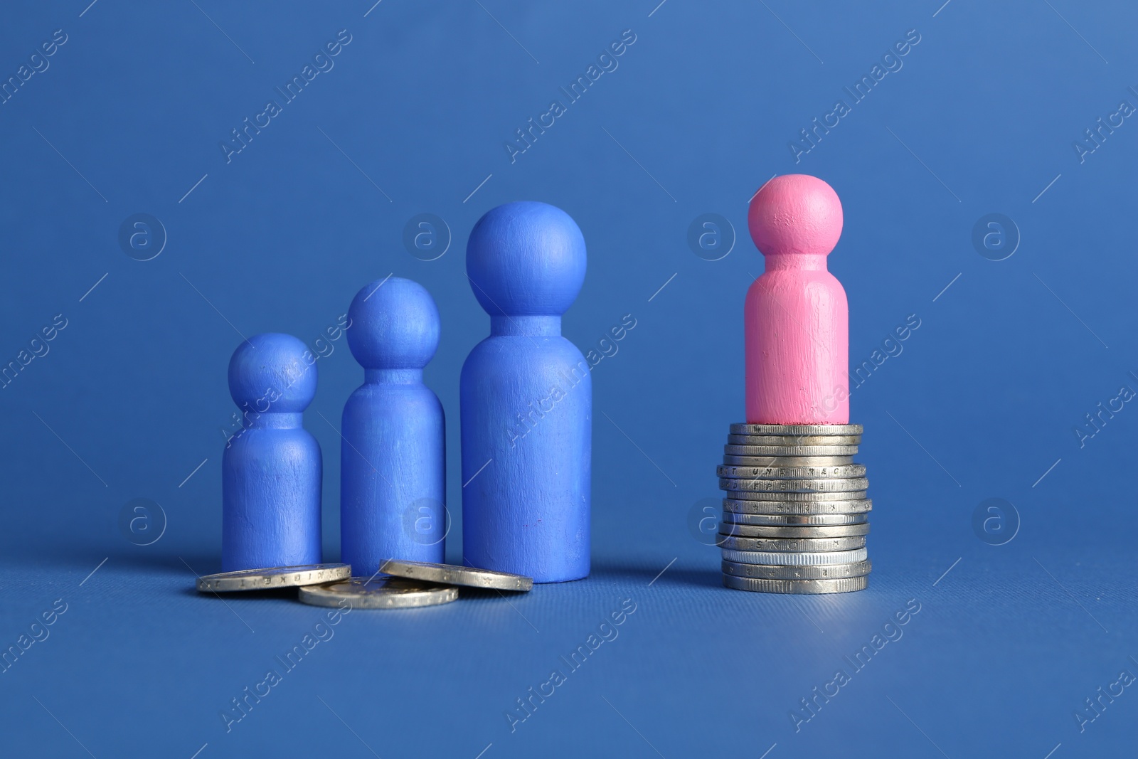 Photo of Financial inequality. Male and female figures with uneven amount of coins on blue background