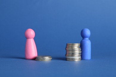 Photo of Financial inequality. Male and female figures on stacked coins of different height against blue background