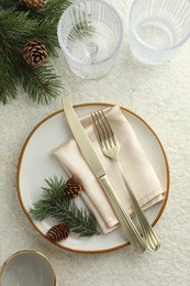 Photo of Christmas table setting with plate, glasses, cutlery, fir branches and cones, flat lay