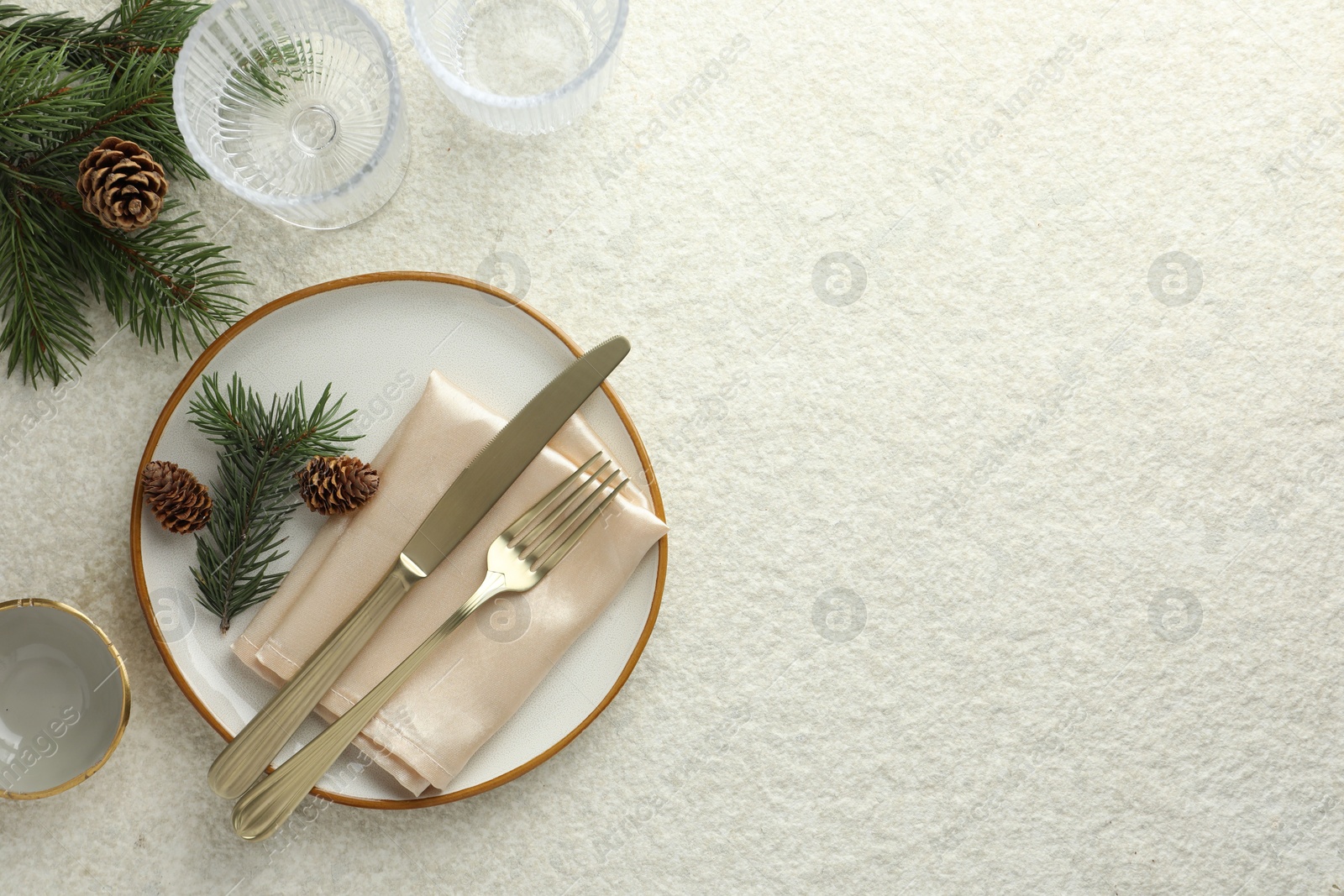 Photo of Christmas table setting with plate, glasses, cutlery, fir branches and cones, flat lay. Space for text