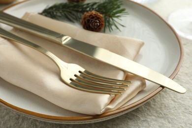 Photo of Christmas table setting with plate, cutlery, fir branches and cones, closeup