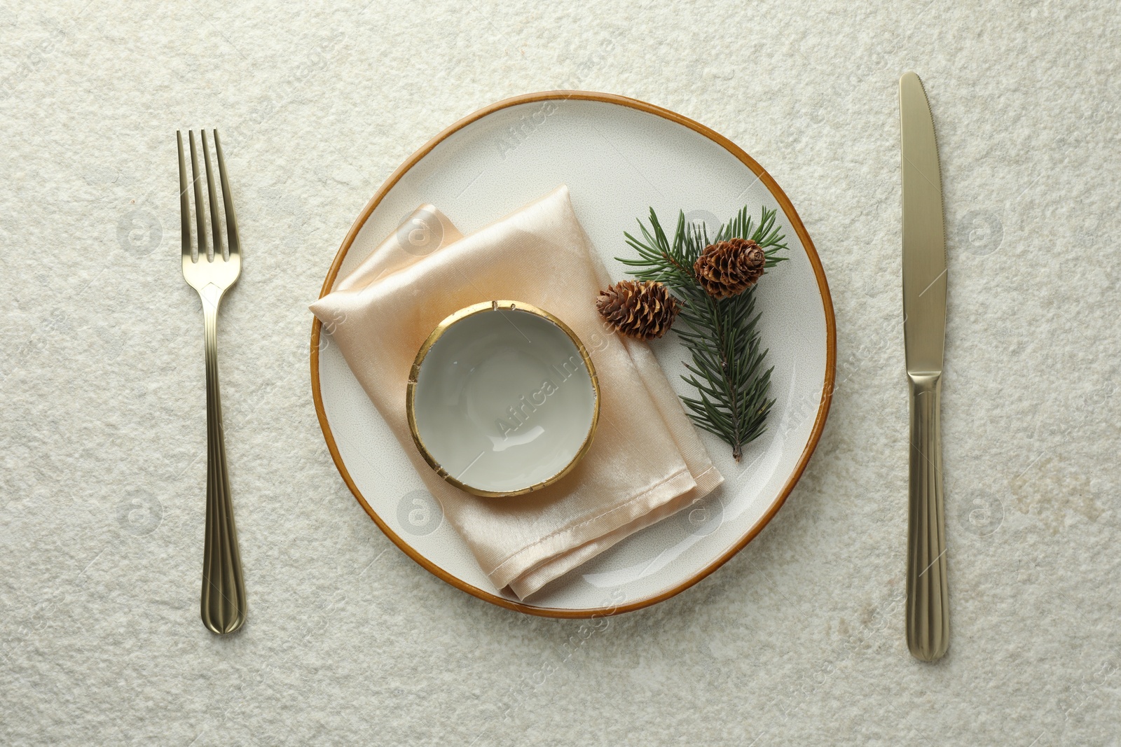 Photo of Christmas table setting with plate, bowl, cutlery, fir branches and cones, flat lay