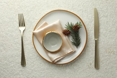 Photo of Christmas table setting with plate, bowl, cutlery, fir branches and cones, flat lay