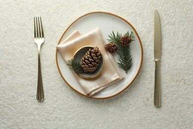 Photo of Christmas table setting with plate, bowl, cutlery, fir branches and cones, flat lay