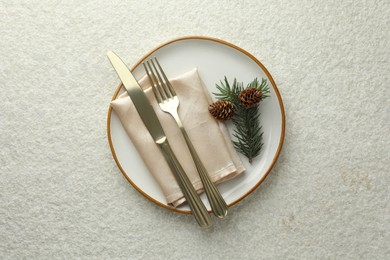 Photo of Christmas table setting with plate, cutlery, fir branch and cones, top view