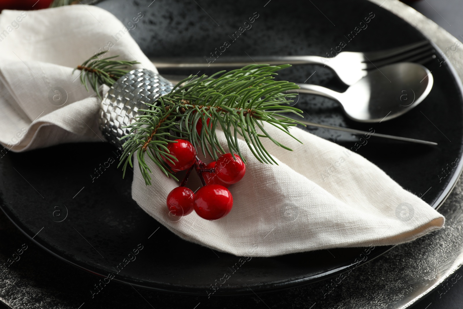 Photo of Christmas table setting. Napkin, fir branches and cutlery on plates, closeup