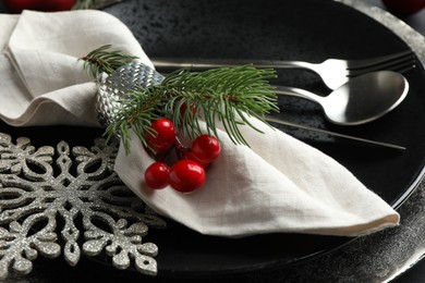 Photo of Christmas table setting. Napkin, fir branches and cutlery on plates, closeup