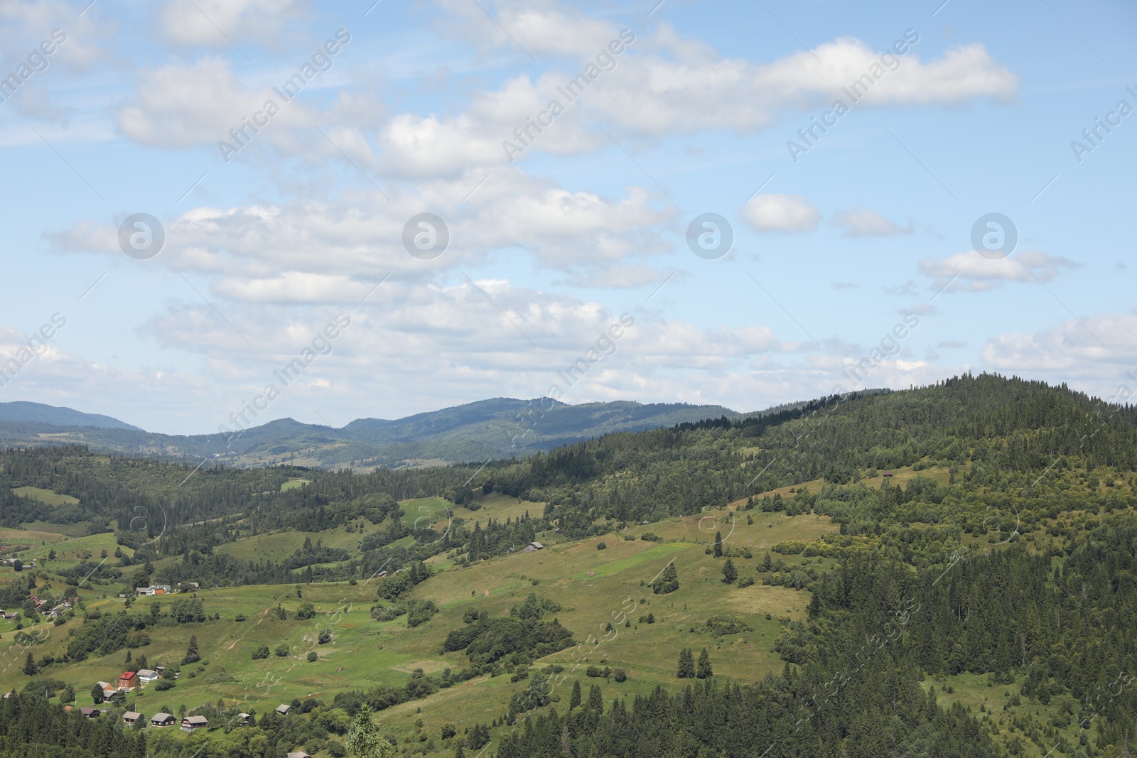 Photo of Picturesque view of houses and forest in mountains under blue sky