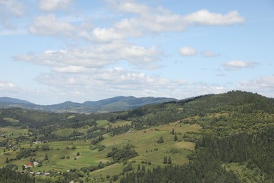 Photo of Picturesque view of houses and forest in mountains under blue sky