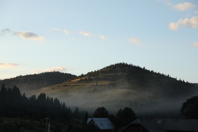 Photo of Picturesque view of fog covering mountain village in morning