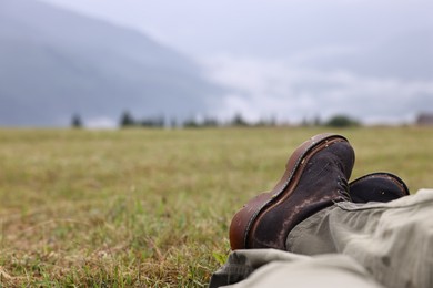 Photo of Man with shoes sitting on grass outdoors, closeup. Space for text