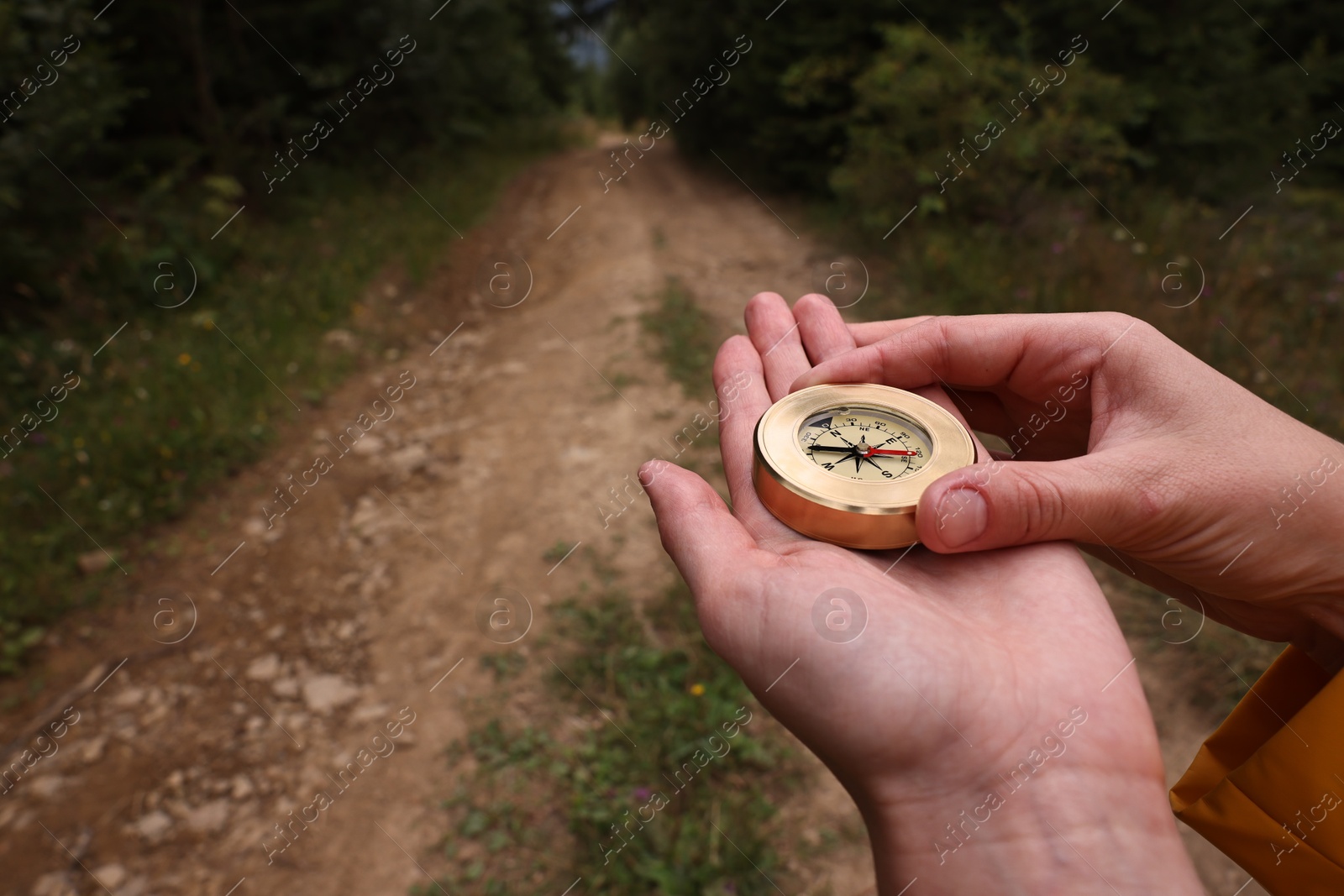 Photo of Woman holding compass near pathway outdoors, closeup. Space for text