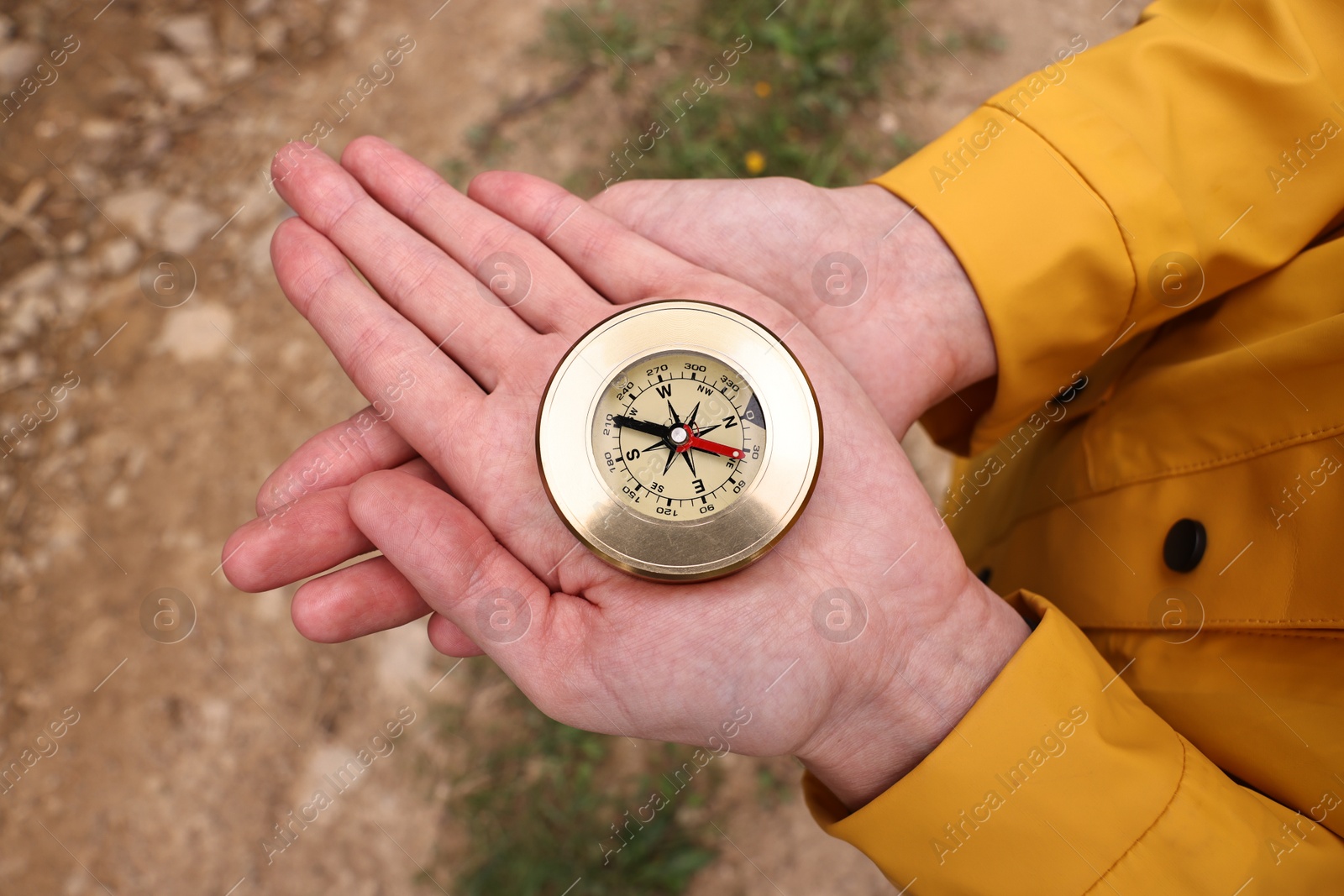 Photo of Woman holding compass near pathway outdoors, closeup