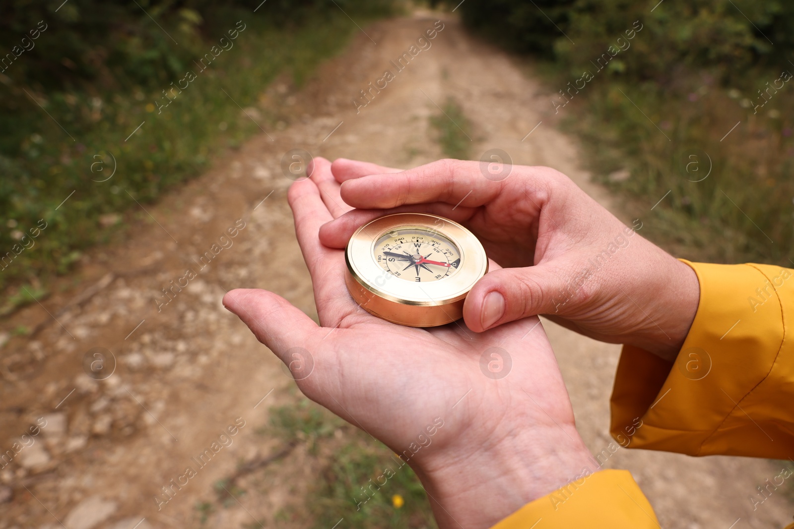 Photo of Woman holding compass near pathway outdoors, closeup