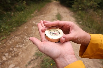 Photo of Woman holding compass near pathway outdoors, closeup