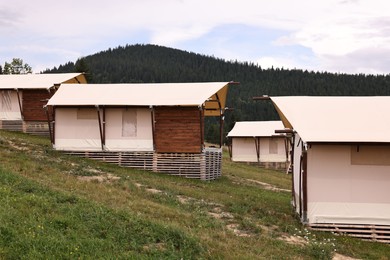 Green forest and many houses in mountains. Glamping site