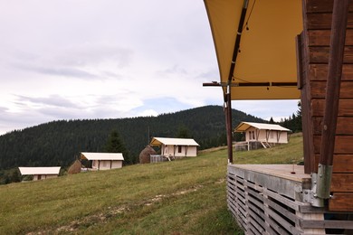 Green forest and many houses in mountains. Glamping site