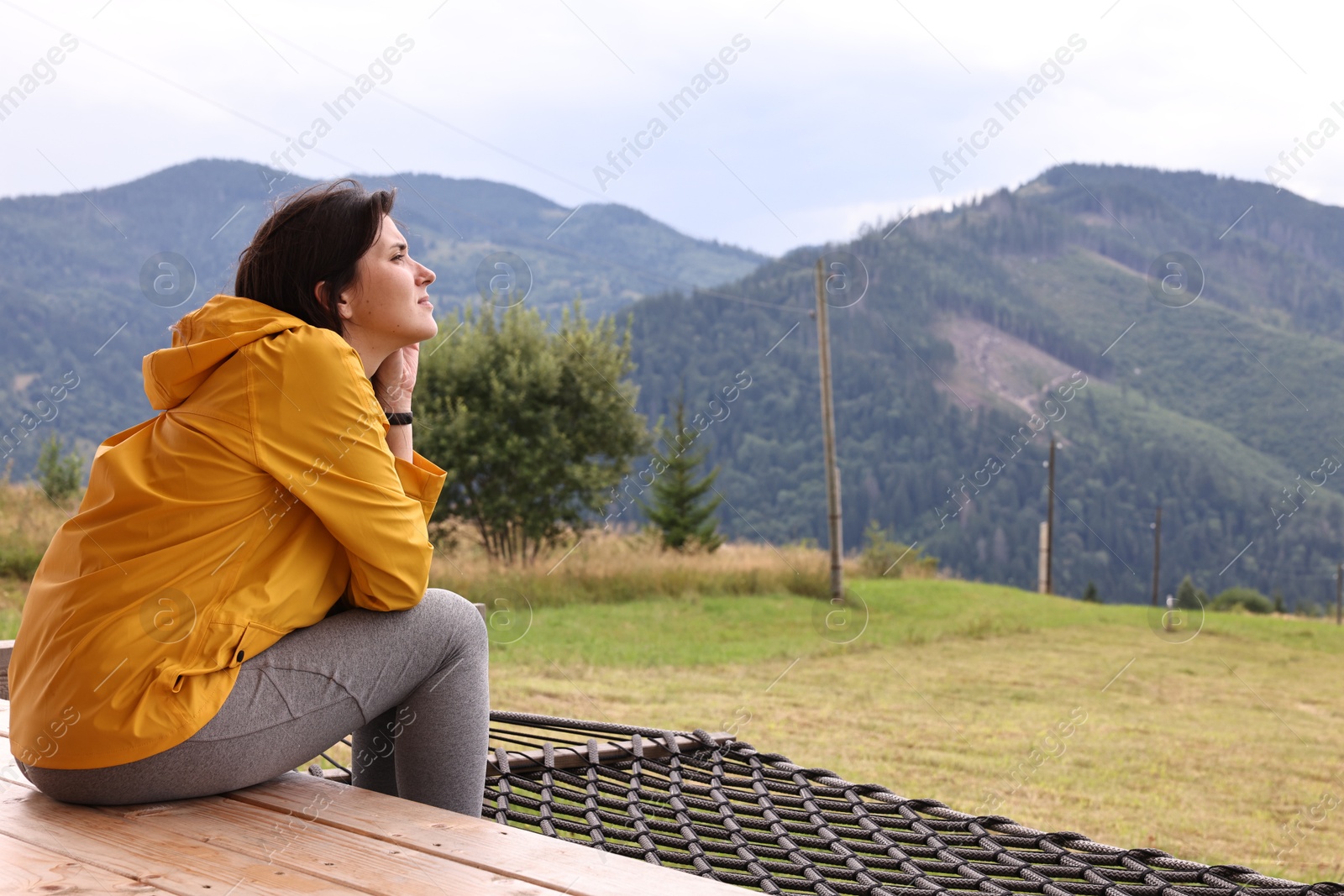 Photo of Young woman sitting on porch in mountains, space for text. Active tourism