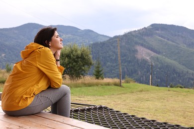 Young woman sitting on porch in mountains, space for text. Active tourism