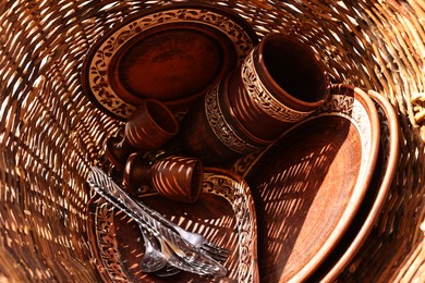 Photo of Wicker basket with different cutlery and tableware, top view