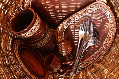 Wicker basket with different cutlery and tableware, top view