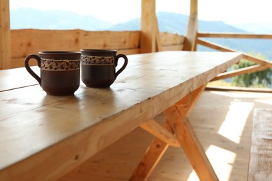 Two cups of hot drink on wooden table in cafe near mountains