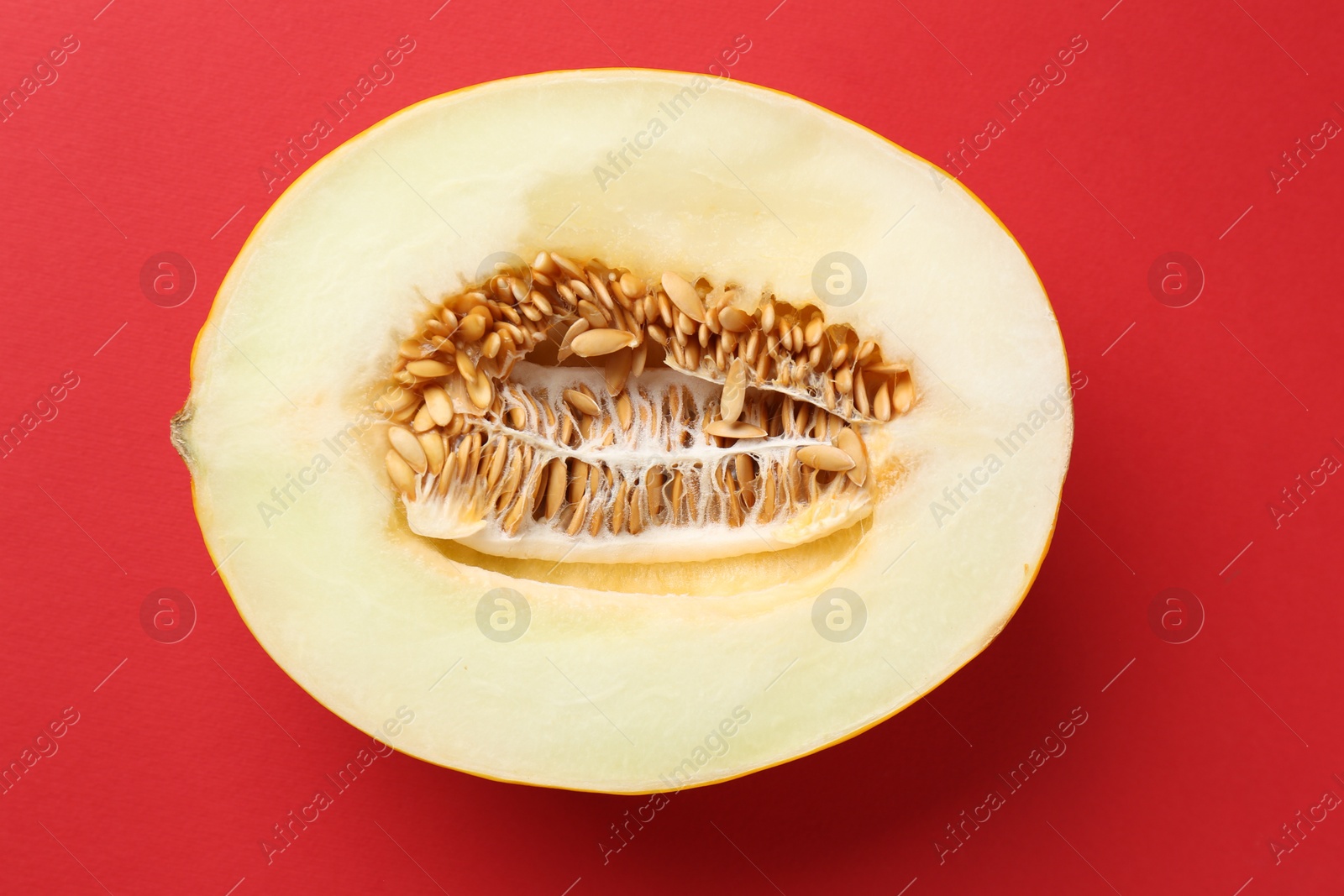 Photo of Half of fresh melon on red background, top view